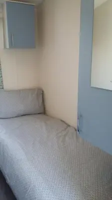 a small bedroom with a bed with a white bedspread at KINGDOM HOLIDAY PARK - Parrot in Millom