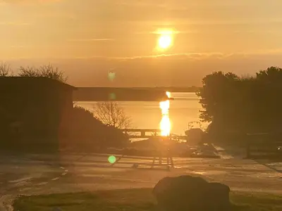 a sunset over the water with a picnic table and a bridge at KINGDOM HOLIDAY PARK - Parrot in Millom