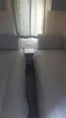 two twin beds in a room with a window at KINGDOM HOLIDAY PARK - Parrot in Millom
