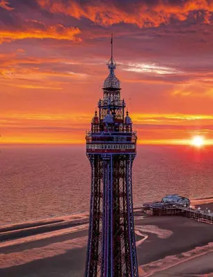 a lighthouse on the beach with the sunset in the background at Ivy Apartments by CityNest in Blackpool