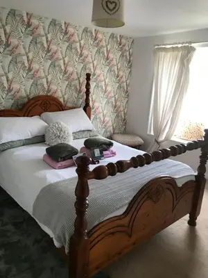 a bedroom with a wooden bed with white sheets at Saltcotes Farm in Ulverston