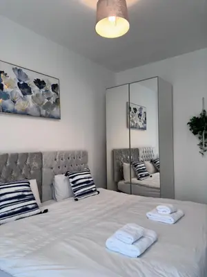 a bedroom with a large white bed with towels on it at Granada Apartments at Pleasure Beach in Blackpool