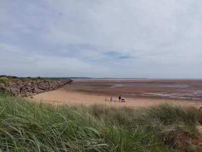 a group of people standing on a sandy beach at Vault 21 in Millom