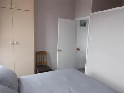 a bedroom with a white bed and a chair at Kelso House holiday flats in Blackpool