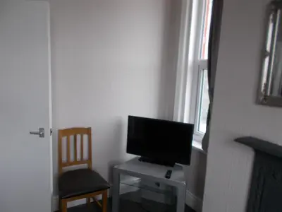 a television sitting on a table in a room with a chair at Kelso House holiday flats in Blackpool