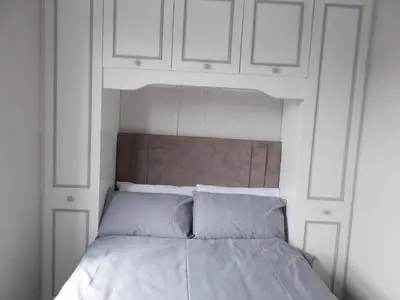 a white bed with white cabinets above it at Kelso House holiday flats in Blackpool