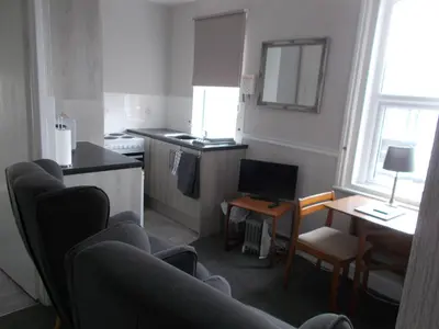 a living room with a kitchen and a table with chairs at Kelso House holiday flats in Blackpool
