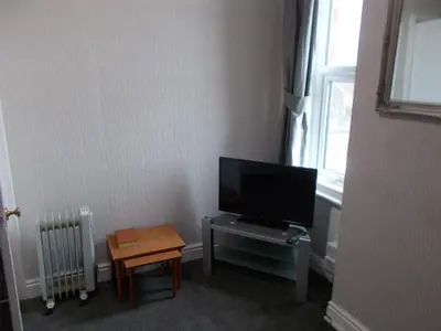 a room with a flat screen tv and a table at Kelso House holiday flats in Blackpool