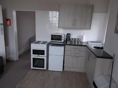 a small kitchen with white appliances and wooden cabinets at Kelso House holiday flats in Blackpool