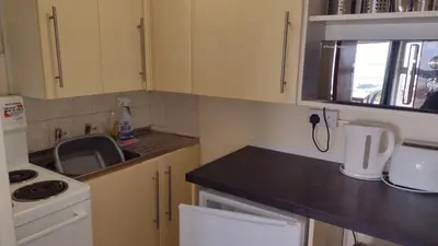 a small kitchen with white cabinets and a sink at The Kathrene Second Floor Sea View in Fleetwood