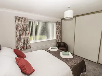 a bedroom with a bed and a chair and a window at Spring Close in Southport