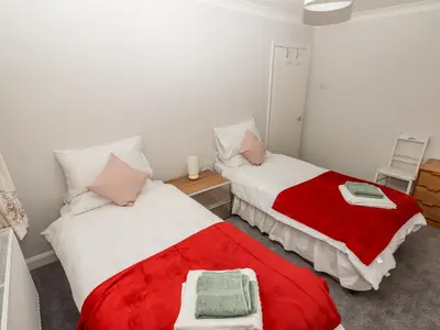 two beds in a room with red and white blankets at Spring Close in Southport