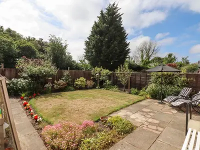 a garden with a lawn with two chairs and an umbrella at Spring Close in Southport