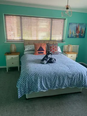 a bedroom with a large bed with blue walls at Seagull’s View in Lytham St Annes