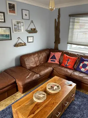 a living room with a brown leather couch and a coffee table at Seagull’s View in Lytham St Annes