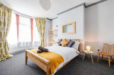 a bedroom with a bed in a room with windows at Knoclaid Sparkle Stays in Liverpool