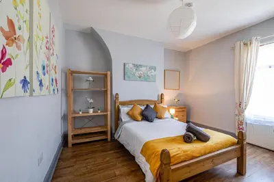 a bedroom with a bed with a wooden bed frame at Knoclaid Sparkle Stays in Liverpool