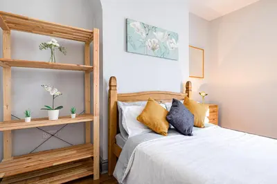 a bedroom with a wooden bed with pillows at Knoclaid Sparkle Stays in Liverpool
