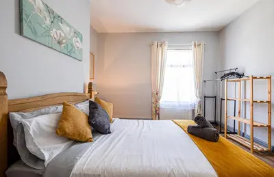 a bedroom with a bed with pillows and a window at Knoclaid Sparkle Stays in Liverpool
