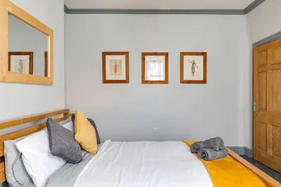 a bedroom with a white bed with three pictures on the wall at Knoclaid Sparkle Stays in Liverpool