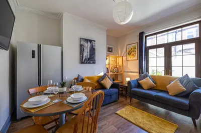 a living room with a table and a blue couch at Knoclaid Sparkle Stays in Liverpool