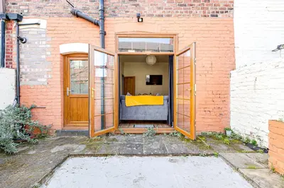 an open door of a brick building with a couch at Knoclaid Sparkle Stays in Liverpool