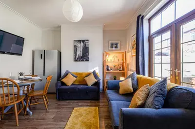 a living room with a blue couch and a table at Knoclaid Sparkle Stays in Liverpool