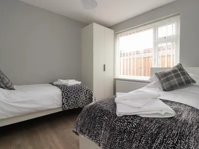 a white bedroom with two beds and a window at Kings Walk in Cleveleys
