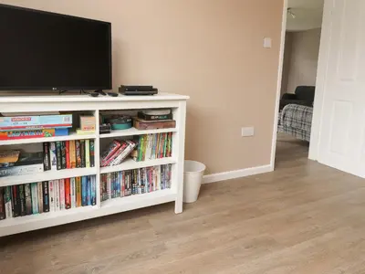 a living room with a tv and a book shelf with dvds at Kings Walk in Cleveleys