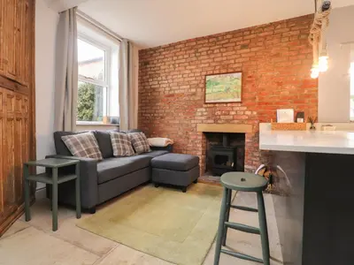 a living room with a couch and a brick wall at The Bothy in Lytham St Annes