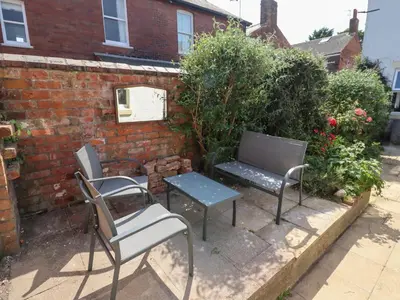 two chairs and a bench in front of a brick wall at The Bothy in Lytham St Annes