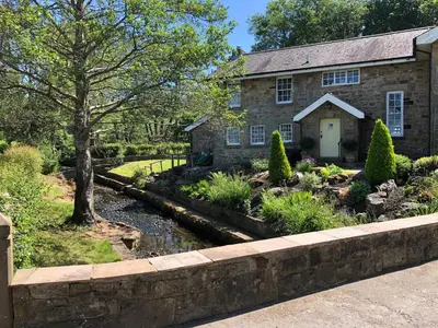a stone house with a stream in front of it at Picket Post House Accommodation in Catterall