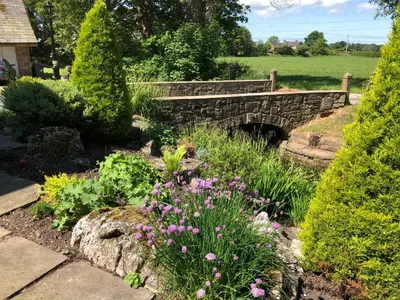 a garden with a stone bridge and flowers at Picket Post House Accommodation in Catterall