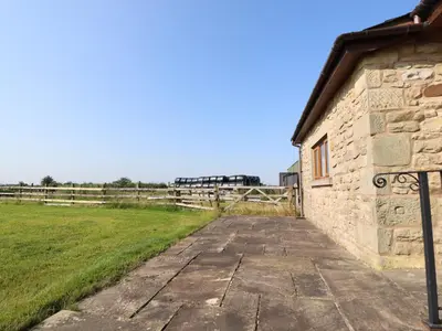 a stone building next to a field with a fence at The Proven House in Preston