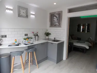 a kitchen with a sink and a counter with stools at Eden Suite Sasco Apartments in Blackpool