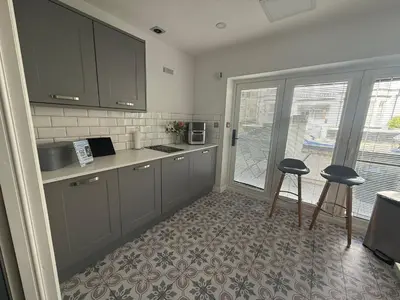 a kitchen with gray cabinets and two stools in it at Eden Suite Sasco Apartments in Blackpool