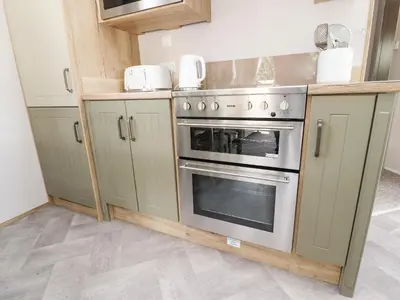 a kitchen with green cabinets and a stainless steel oven at 25 Sherwood in Carnforth