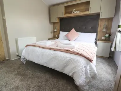 a bedroom with a large bed with white sheets and pink pillows at 25 Sherwood in Carnforth