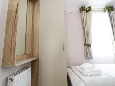 a bedroom with a bed and a mirror and a window at 25 Sherwood in Carnforth