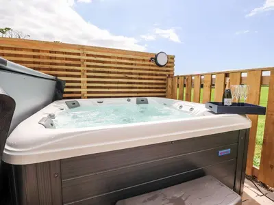 a hot tub in a backyard with a fence at Box Tree Escapes in Lancaster