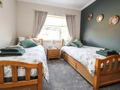 two beds in a room with a window at 2 Pine Grove in Preston