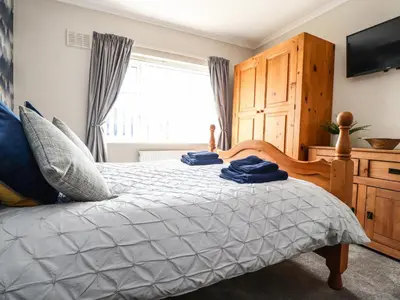 a bedroom with a bed and a television and a window at 2 Pine Grove in Preston