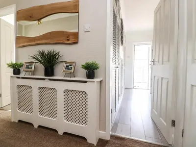 a hallway with a mirror and a table with plants at 2 Pine Grove in Preston