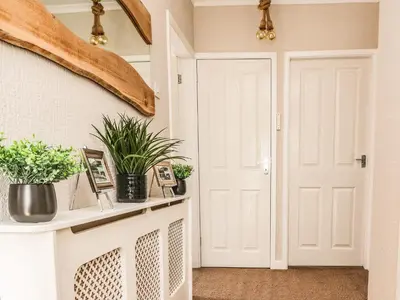 a hallway with a white door and potted plants at 2 Pine Grove in Preston
