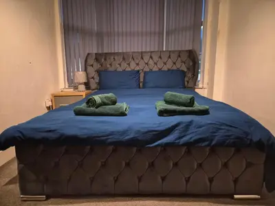 a large bed with two green pillows on it at Blackpool Apartments in Blackpool