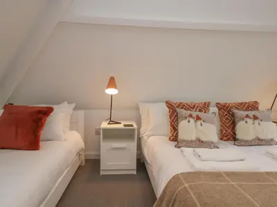 a bedroom with two beds and a lamp at Moorhurst Cottage in Grange Over Sands