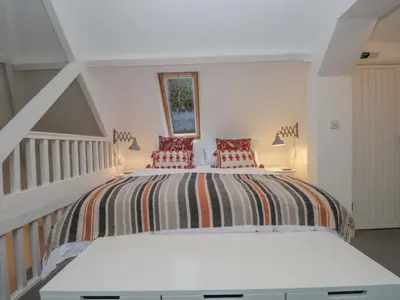 a bedroom with a large bed with a striped blanket at Moorhurst Cottage in Grange Over Sands