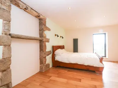a bedroom with a bed and a stone wall at Bowland Barn in Lancaster