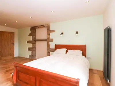 a bedroom with a large bed with white sheets at Bowland Barn in Lancaster