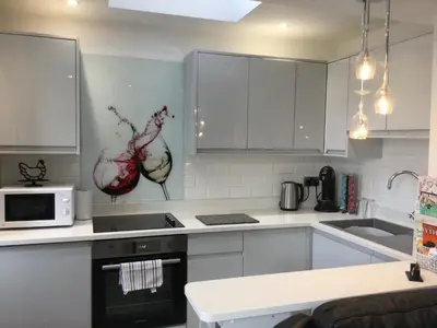 a kitchen with white cabinets and a stove top oven at Leafy Lytham central Lovely ground floor 1 bedroom apartment with private garden In Lytham dog friendly in Lytham St Annes